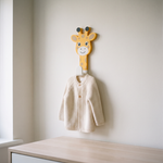 Cabideiro de girafa na parede do quarto com casaquinho pendurado